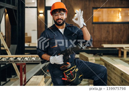 White gloves are on hands. Portrait of a male carpenter posing in a woodworking workshop White gloves are on hands. Portrait of a male carpenter posing in a woodworking workshop 139975798