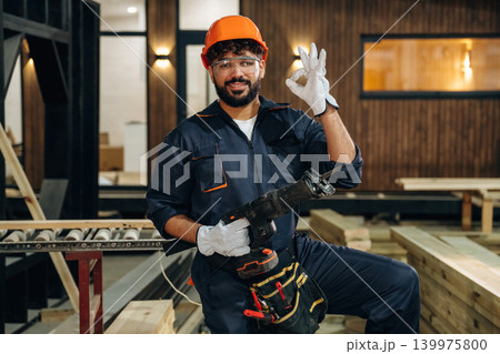 White gloves are on hands. Portrait of a male carpenter posing in a woodworking workshop White gloves are on hands. Portrait of a male carpenter posing in a woodworking workshop 139975800