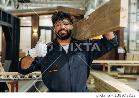Thumb up hand gesture. Male carpenter working with wooden materials in a professional workshop Thumb up hand gesture. Male carpenter working with wooden materials in a professional workshop 139975815