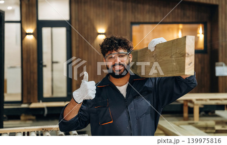 Thumb up hand gesture. Male carpenter working with wooden materials in a professional workshop 139975816