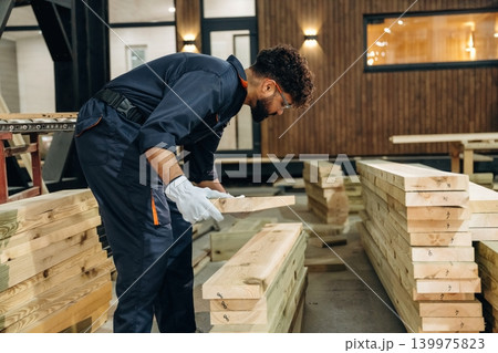 Male carpenter working with wooden materials in a professional workshop Male carpenter working with wooden materials in a professional workshop 139975823