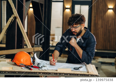Smart engineer is working with plan. Male carpenter working with wooden materials in a professional workshop Smart engineer is working with plan. Male carpenter working with wooden materials in a professional workshop 139975838