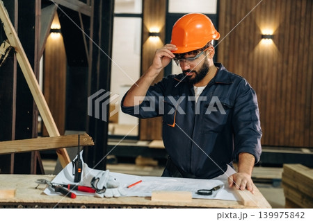 Employee is busy. Male carpenter working with wooden materials in a professional workshop 139975842