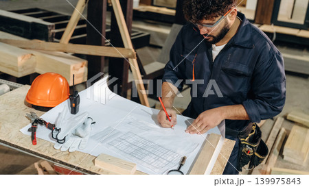 Smart engineer is working with plan. Male carpenter working with wooden materials in a professional workshop Smart engineer is working with plan. Male carpenter working with wooden materials in a professional workshop 139975843