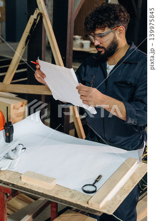 Smart engineer is working with plan. Male carpenter working with wooden materials in a professional workshop Smart engineer is working with plan. Male carpenter working with wooden materials in a professional workshop 139975845