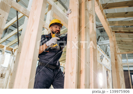 Modern professional drill is in hands. Male carpenter working with wooden materials in a professional workshop 139975906