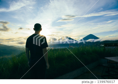 Person watches sunset over mountains and clouds in Bali Person watches sunset over mountains and clouds in Bali 139976017
