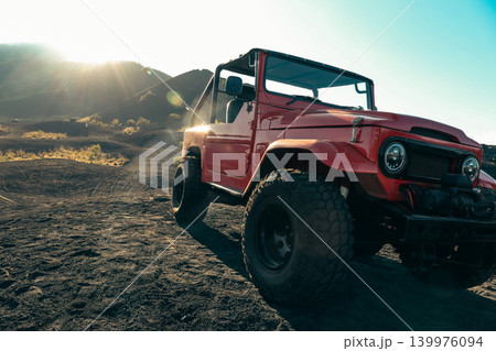 Red jeep parked on a dirt road in Kintamani Bali at sunrise Red jeep parked on a dirt road in Kintamani Bali at sunrise 139976094