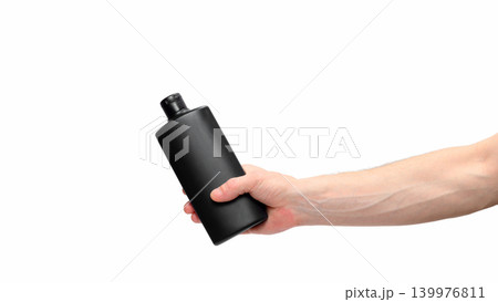 human hand holds a tilted black plastic container on a white background 139976811
