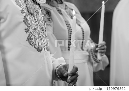 Two People in Traditional Embroidered White Tunics Holding Lit Candles in Black and White Style Two People in Traditional Embroidered White Tunics Holding Lit Candles in Black and White Style 139976862