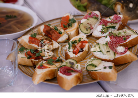 Assorted Bruschetta Appetizers with Salami, Smoked Salmon, and Cucumber on a Ceramic Plate Assorted Bruschetta Appetizers with Salami, Smoked Salmon, and Cucumber on a Ceramic Plate 139976876