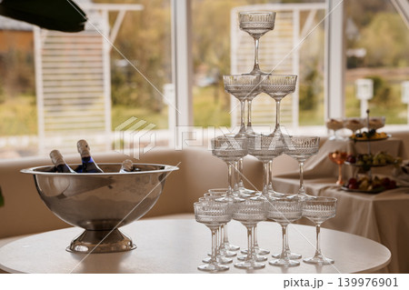 Champagne Coupe Pyramid Tower and Silver Ice Bucket with Bottles on White Table at Outdoor Event Champagne Coupe Pyramid Tower and Silver Ice Bucket with Bottles on White Table at Outdoor Event 139976901