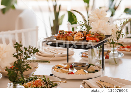 Gourmet Salmon Crostini and Cheese Platter on Elegant White Table with Floral Decor 139976908
