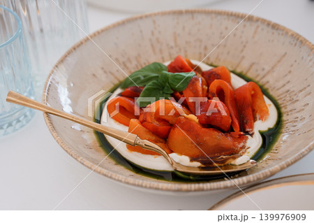 Roasted Red Peppers with Creamy White Sauce and Fresh Basil in a Rustic Ceramic Bowl 139976909