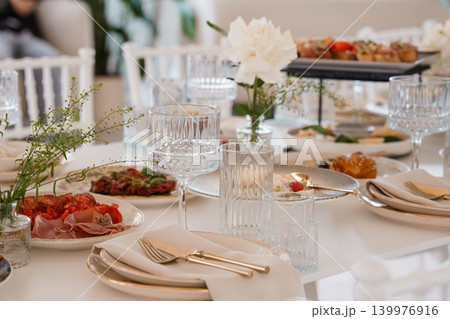 Elegant Wedding Table Setting with White Flowers, Charcuterie, and Crystal Glassware in Bright Light Elegant Wedding Table Setting with White Flowers, Charcuterie, and Crystal Glassware in Bright Light 139976916
