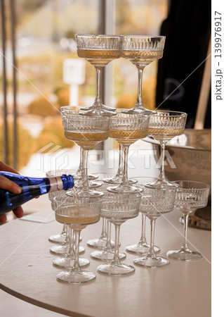 Hand Pouring Sparkling Champagne Into Stacked Crystal Coupes For Celebration 139976917