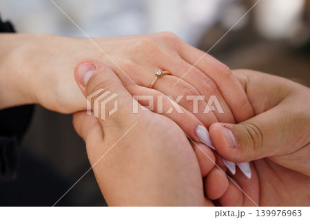 Close Up of Couple Holding Hands with Diamond Engagement Ring on Woman Finger in Soft Natural Light Close Up of Couple Holding Hands with Diamond Engagement Ring on Woman Finger in Soft Natural Light 139976963