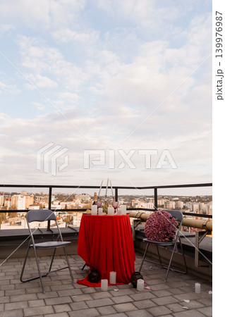 Romantic Dinner for Two with Red Tablecloth and Roses on Rooftop Terrace overlooking City Skyline Romantic Dinner for Two with Red Tablecloth and Roses on Rooftop Terrace overlooking City Skyline 139976987