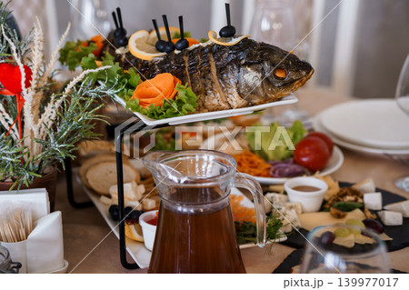 Roasted Whole Fish with Lemon and Olives Served on a Multi-Tiered Buffet Platter at a Festive Dinner 139977017