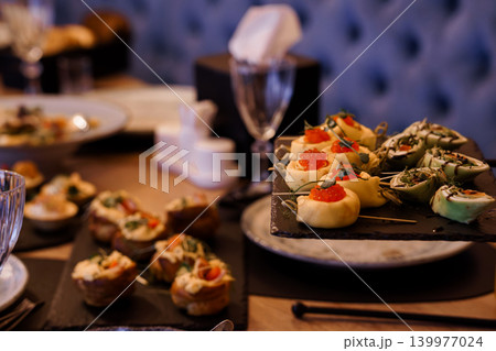 Gourmet Appetizer Platter with Red Caviar and Creamy Pastry on Slate Board in Dimly Lit Restaurant Gourmet Appetizer Platter with Red Caviar and Creamy Pastry on Slate Board in Dimly Lit Restaurant 139977024