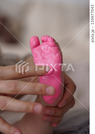 Close up of Toddler Foot Painted in Pink Color with Adult Hands Holding Small Feet Close up of Toddler Foot Painted in Pink Color with Adult Hands Holding Small Feet 139977043