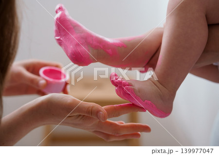 Mother Applying Pink Cream to Baby Feet During Skincare Routine for Soft Skin Care 139977047
