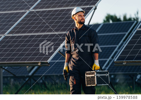 Ready for work, holding box with tools. Male solar engineer examining photovoltaic panels at a power station 139978588