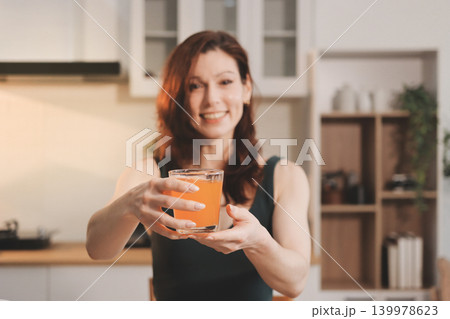 Woman preparing green smoothie in bright kitchen with fresh fruits and vegetables, healthy eating lifestyle moment in natural daylight Woman preparing green smoothie in bright kitchen with fresh fruits and vegetables, healthy eating lifestyle moment in natural daylight 139978623
