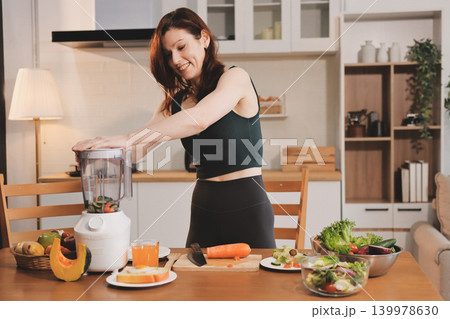 Woman preparing green smoothie in bright kitchen with fresh fruits and vegetables, healthy eating lifestyle moment in natural daylight 139978630