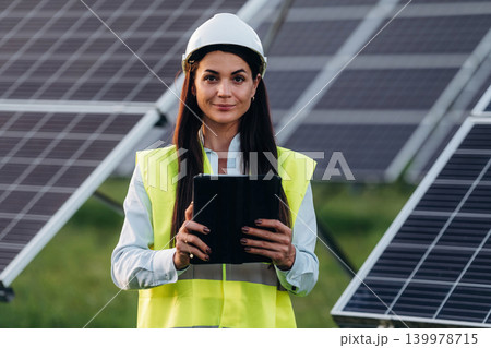 Female solar engineer inspecting photovoltaic panels during outdoor maintenance work 139978715