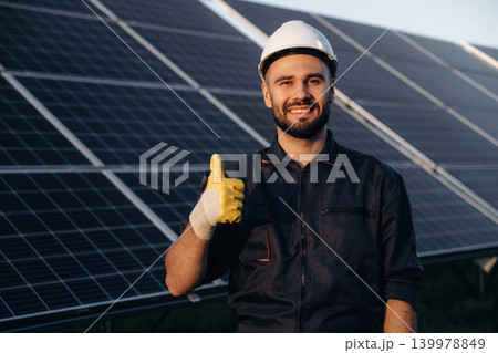 Thumb up gesture. Male solar engineer examining photovoltaic panels at a power station 139978849