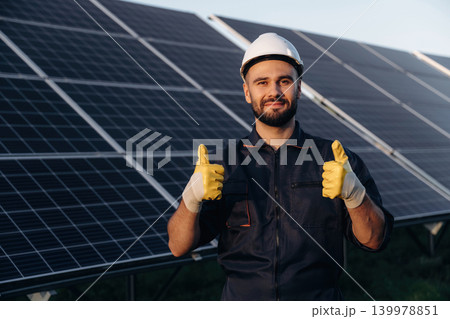 Thumb up gesture. Male solar engineer examining photovoltaic panels at a power station Thumb up gesture. Male solar engineer examining photovoltaic panels at a power station 139978851