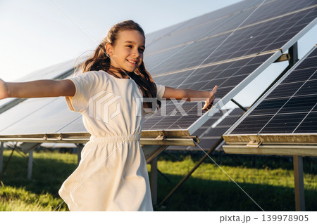 Happy girl is near renewable energy equipment under bright sunlight Happy girl is near renewable energy equipment under bright sunlight 139978905