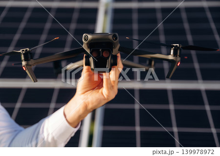 The drone is in the hand. Male solar engineer examining photovoltaic panels at a power station The drone is in the hand. Male solar engineer examining photovoltaic panels at a power station 139978972