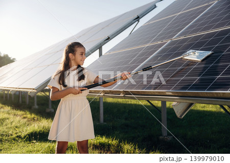 Washing, cleaning the surface. Happy girl is near renewable energy equipment under bright sunlight Washing, cleaning the surface. Happy girl is near renewable energy equipment under bright sunlight 139979010