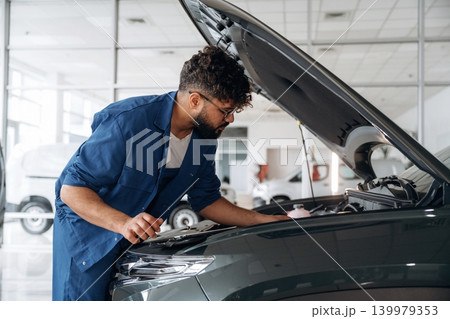Hood is opened. Auto service specialist examining vehicle condition Hood is opened. Auto service specialist examining vehicle condition 139979353