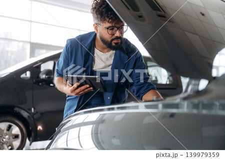 Auto service specialist examining vehicle condition Auto service specialist examining vehicle condition 139979359