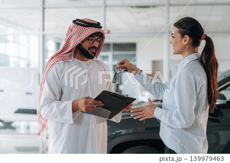 Middle eastern client discussing car purchase in modern dealership Middle eastern client discussing car purchase in modern dealership 139979463
