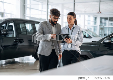 Helping a male customer. Business consultation between car dealer and buyer in showroom 139979480