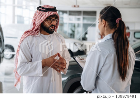 Premium class automobiles. Middle eastern client discussing car purchase in modern dealership Premium class automobiles. Middle eastern client discussing car purchase in modern dealership 139979491