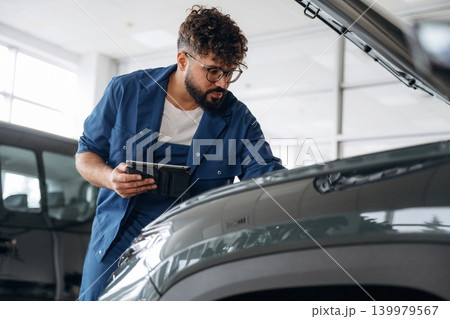 Black digital tablet is in hands. Auto service specialist examining vehicle condition Black digital tablet is in hands. Auto service specialist examining vehicle condition 139979567