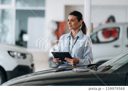 Front view. Successful automotive consultant standing near car interior Front view. Successful automotive consultant standing near car interior 139979568
