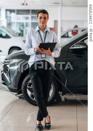 Front view. Successful automotive consultant standing near car interior Front view. Successful automotive consultant standing near car interior 139979569