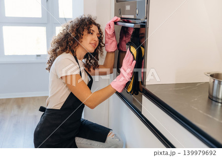 Routine time. White woman cleaning the kitchen countertop with spray and cloth wearing pink gloves Routine time. White woman cleaning the kitchen countertop with spray and cloth wearing pink gloves 139979692