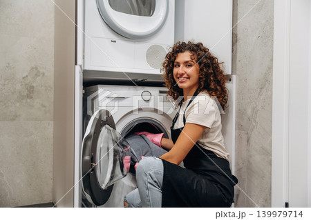 Smiling, cheerful facial expression. At home. Woman doing laundry with washing machine at home 139979714