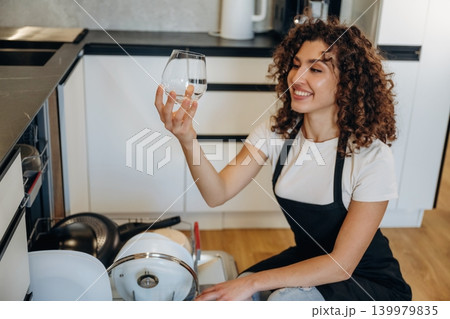 Female loading dishwasher in bright modern kitchen 139979835