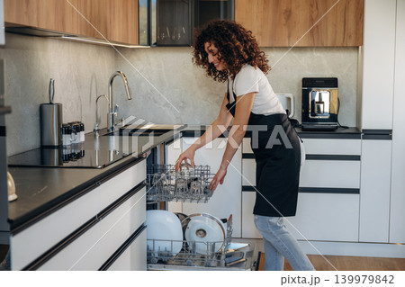 View from the side. Female loading dishwasher in bright modern kitchen 139979842