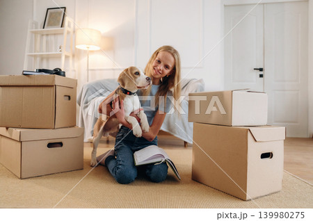 Holding animal in hands, embracing. Girl is with her dog on the floor in a cozy living room Holding animal in hands, embracing. Girl is with her dog on the floor in a cozy living room 139980275