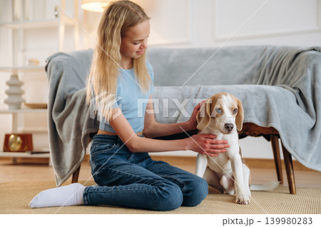Girl is with her dog on the floor in a cozy living room Girl is with her dog on the floor in a cozy living room 139980283