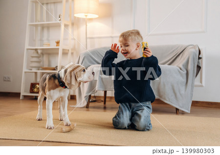 Having fun. Cute little boy playing with dog at home on the floor 139980303